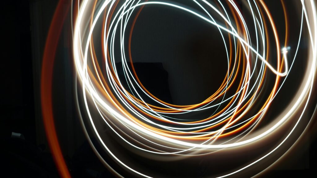 Dynamic long exposure shot of swirling light streaks creating an abstract pattern on a dark background.